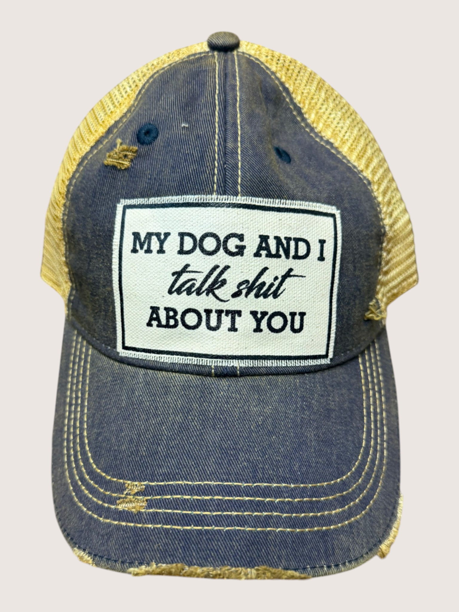 Blue and yellow cap with a humorous patch on a light gray background