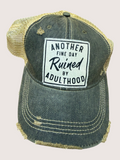 Distressed denim cap with gold mesh back and humorous patch on a light gray background