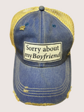 Blue denim cap with yellow mesh back and 'Sorry about my boyfriend' patch on a light gray background