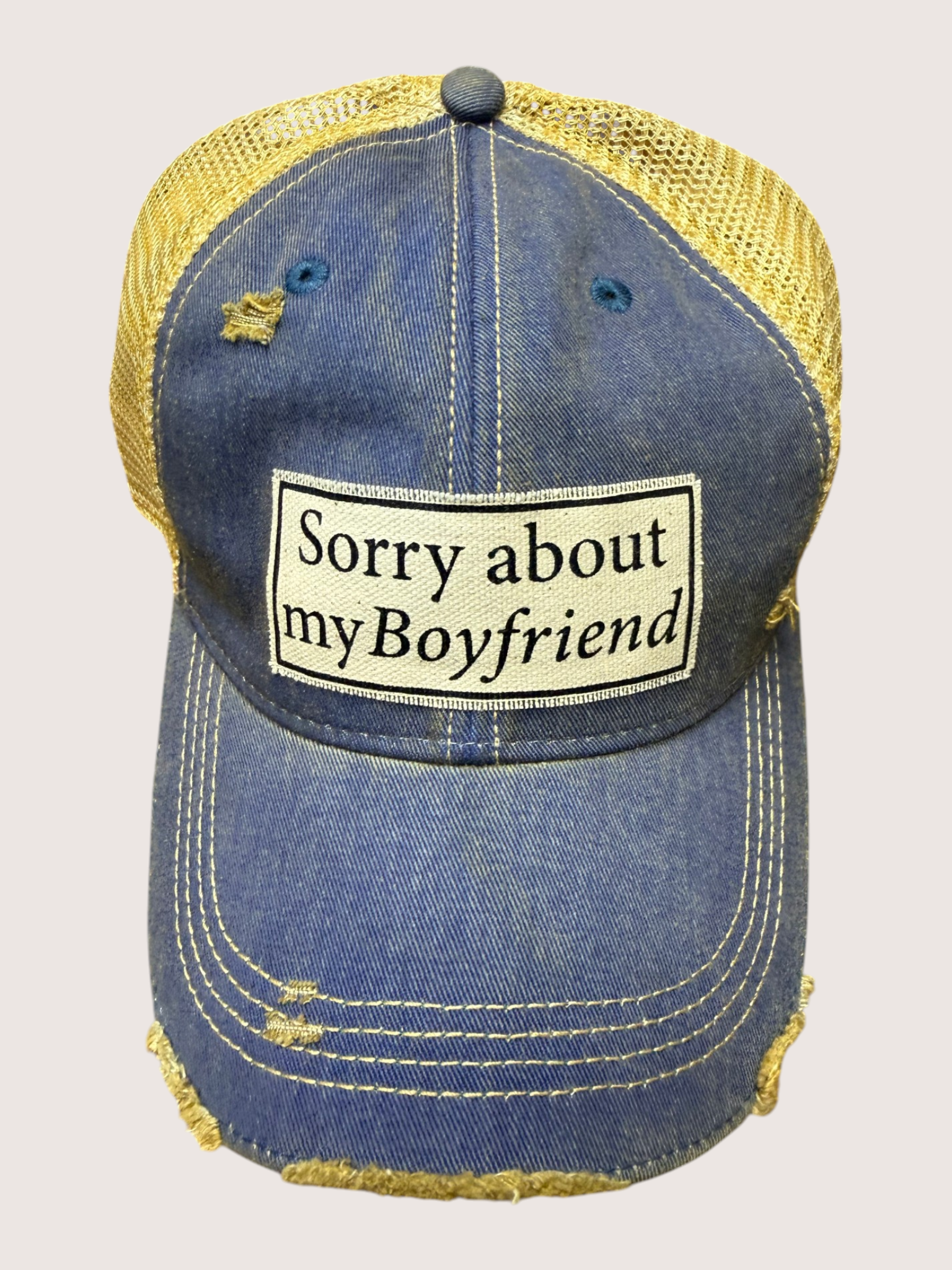 Blue denim cap with yellow mesh back and 'Sorry about my boyfriend' patch on a light gray background