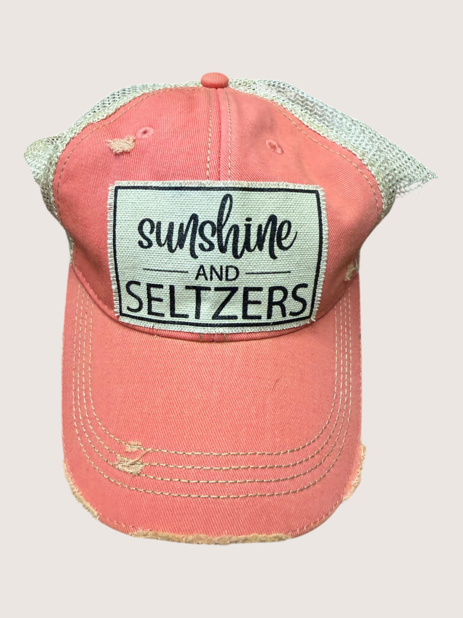 Pink cap with 'Sunshine and Seltzers' patch on a light gray background