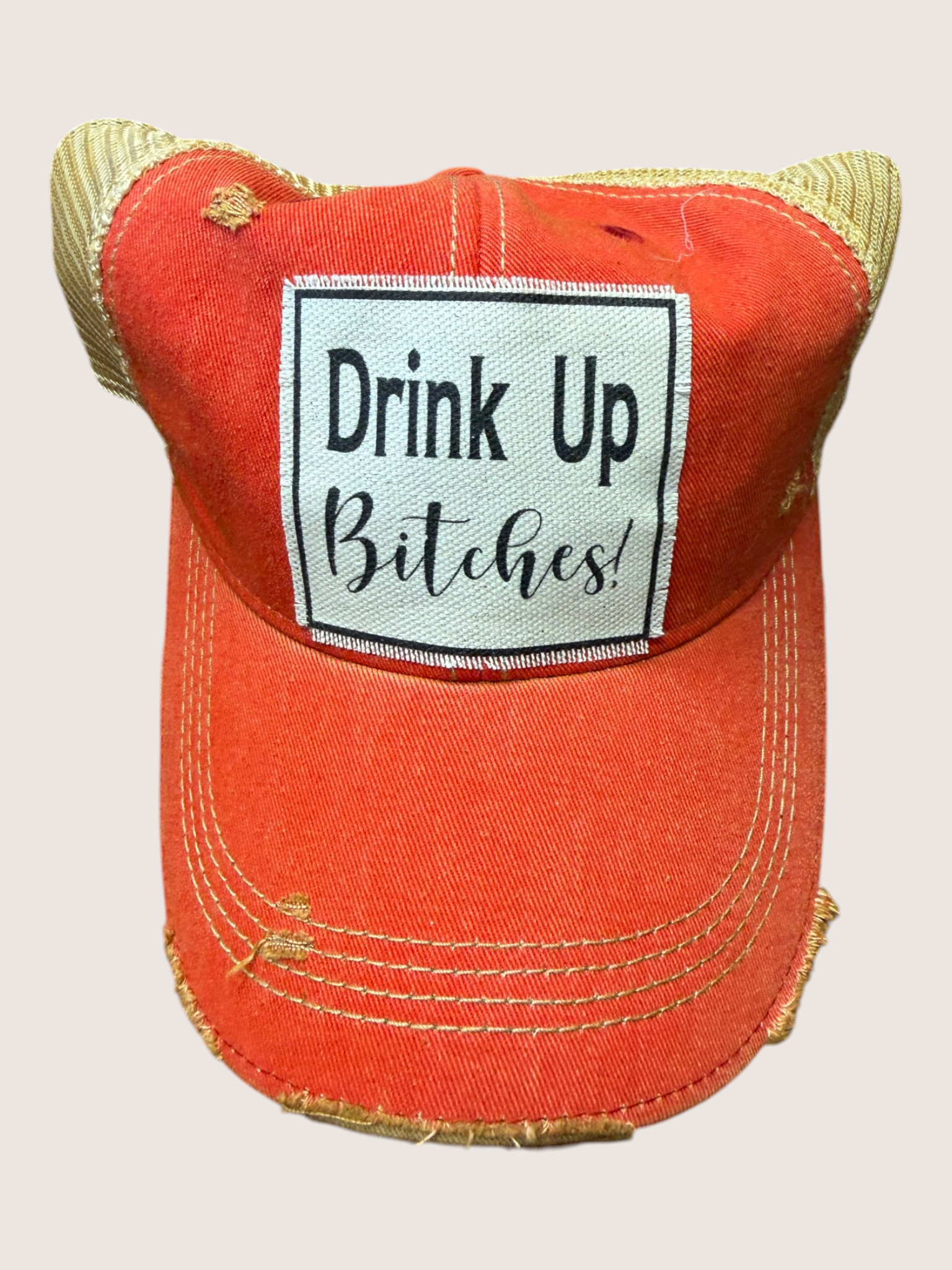 Red distressed baseball cap with 'Drink Up Bitches!' patch on a light gray background