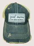 Blue denim cap with yellow mesh back and 'good moms say bad words' patch on a beige background