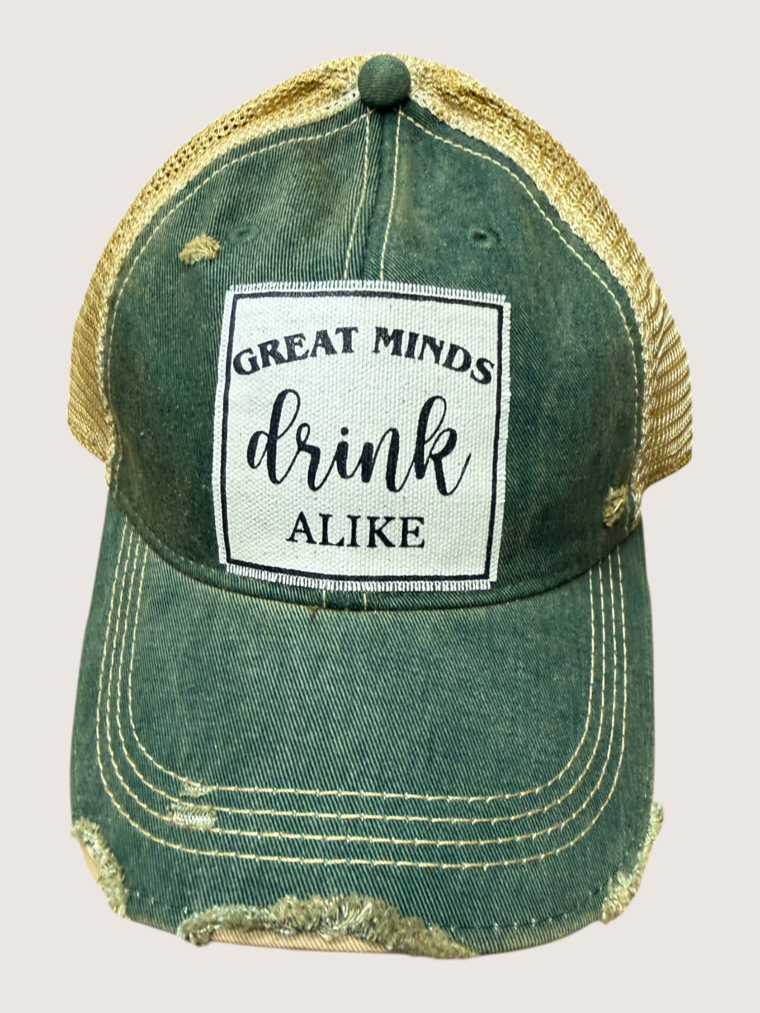 Green and gold cap with a patch that says 'Great minds drink alike' on a light gray background