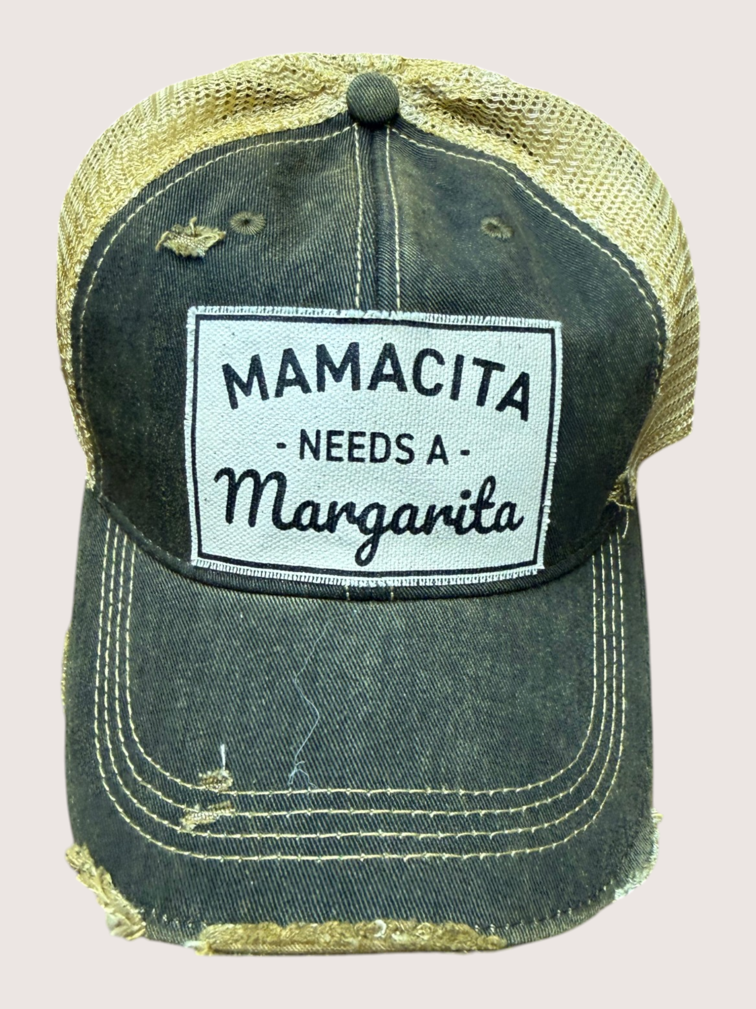 Black distressed trucker cap with 'Mamacita Needs a Margarita' text on a light gray background