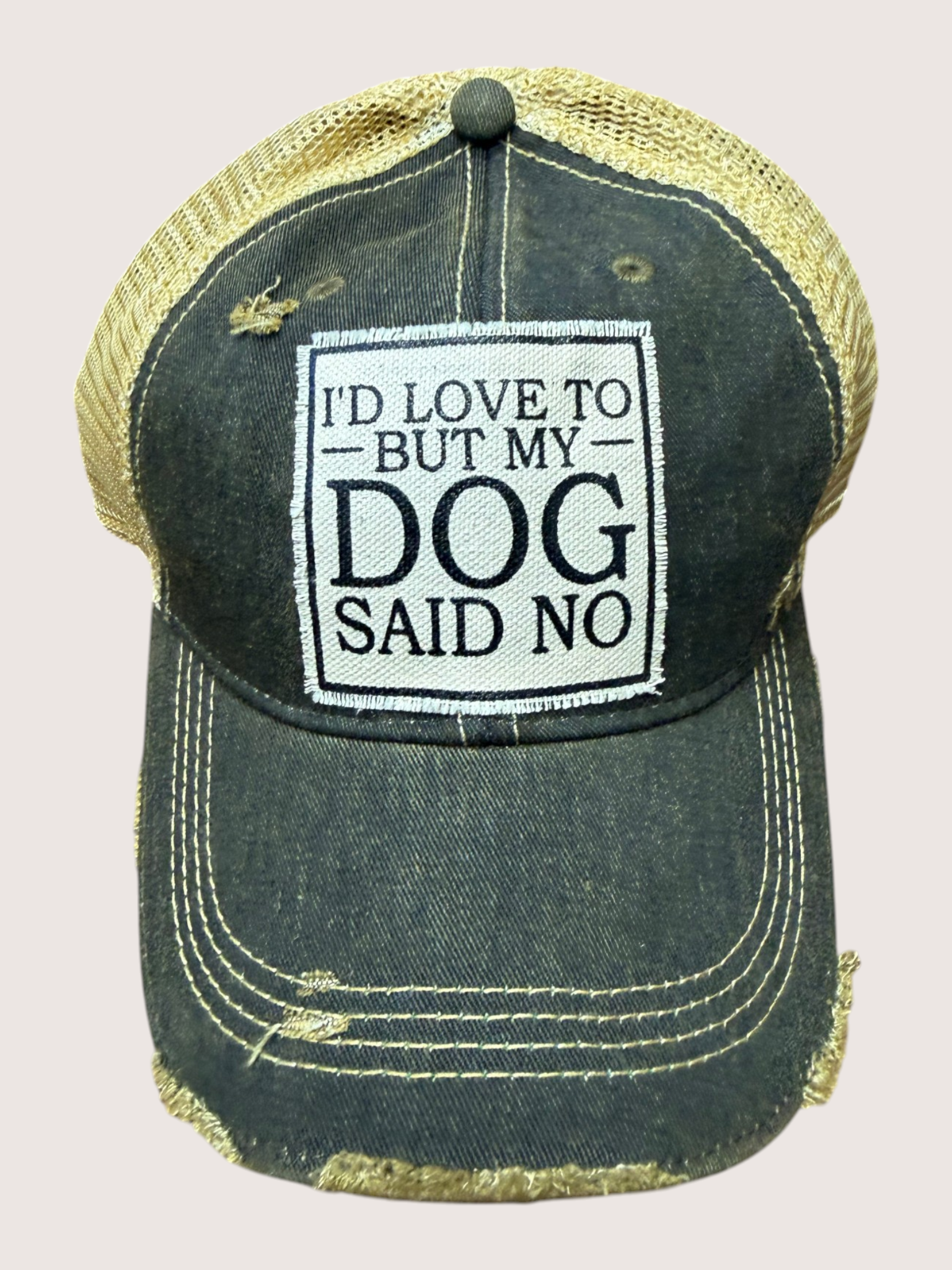 Black distressed cap with 'I'd love to, but my dog said no' text on a beige background