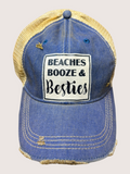 Blue denim cap with yellow mesh back and 'Beaches Booze & Besties' text on a light gray background