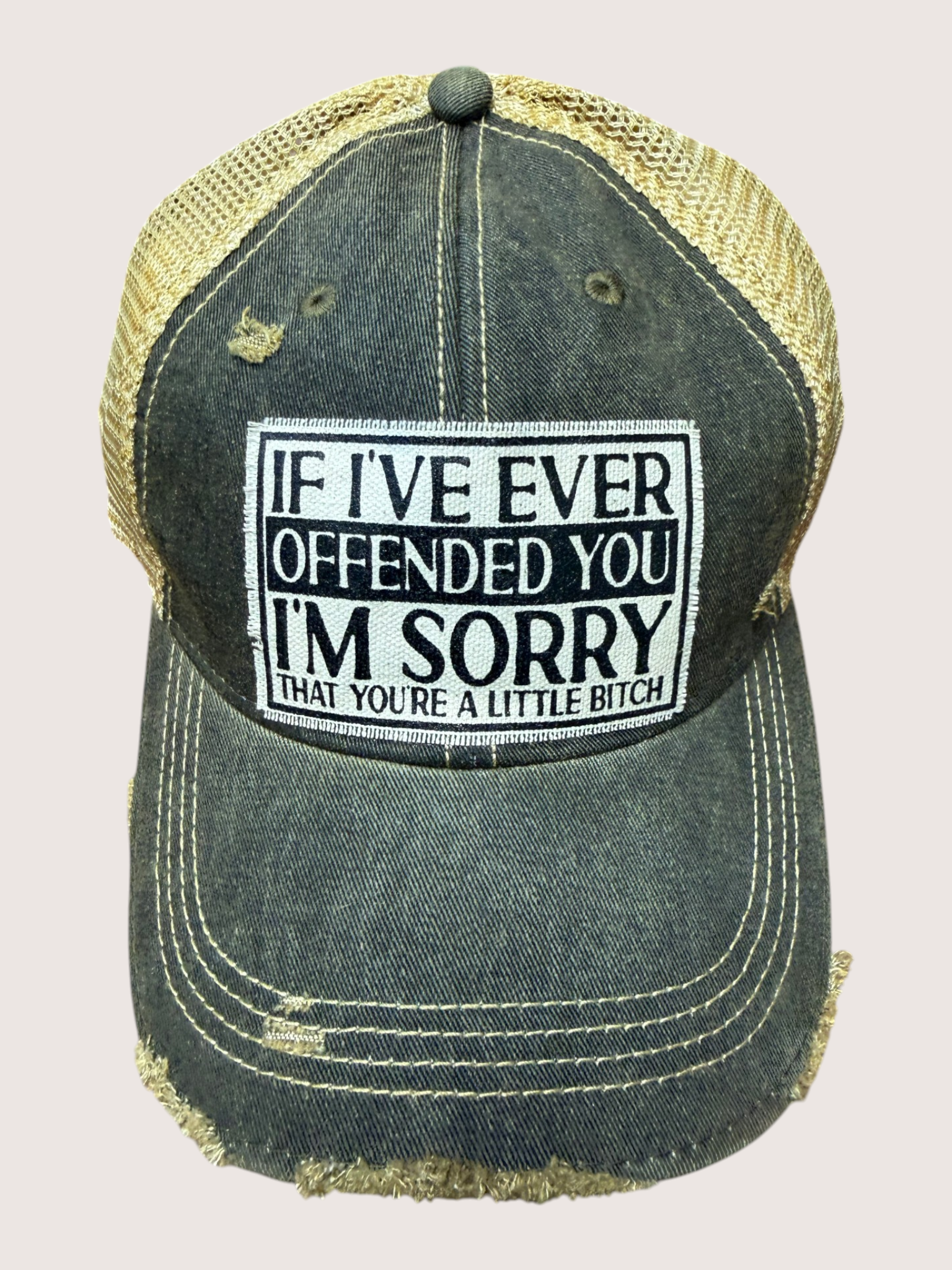 Black and gold cap with a humorous text patch on a light gray background