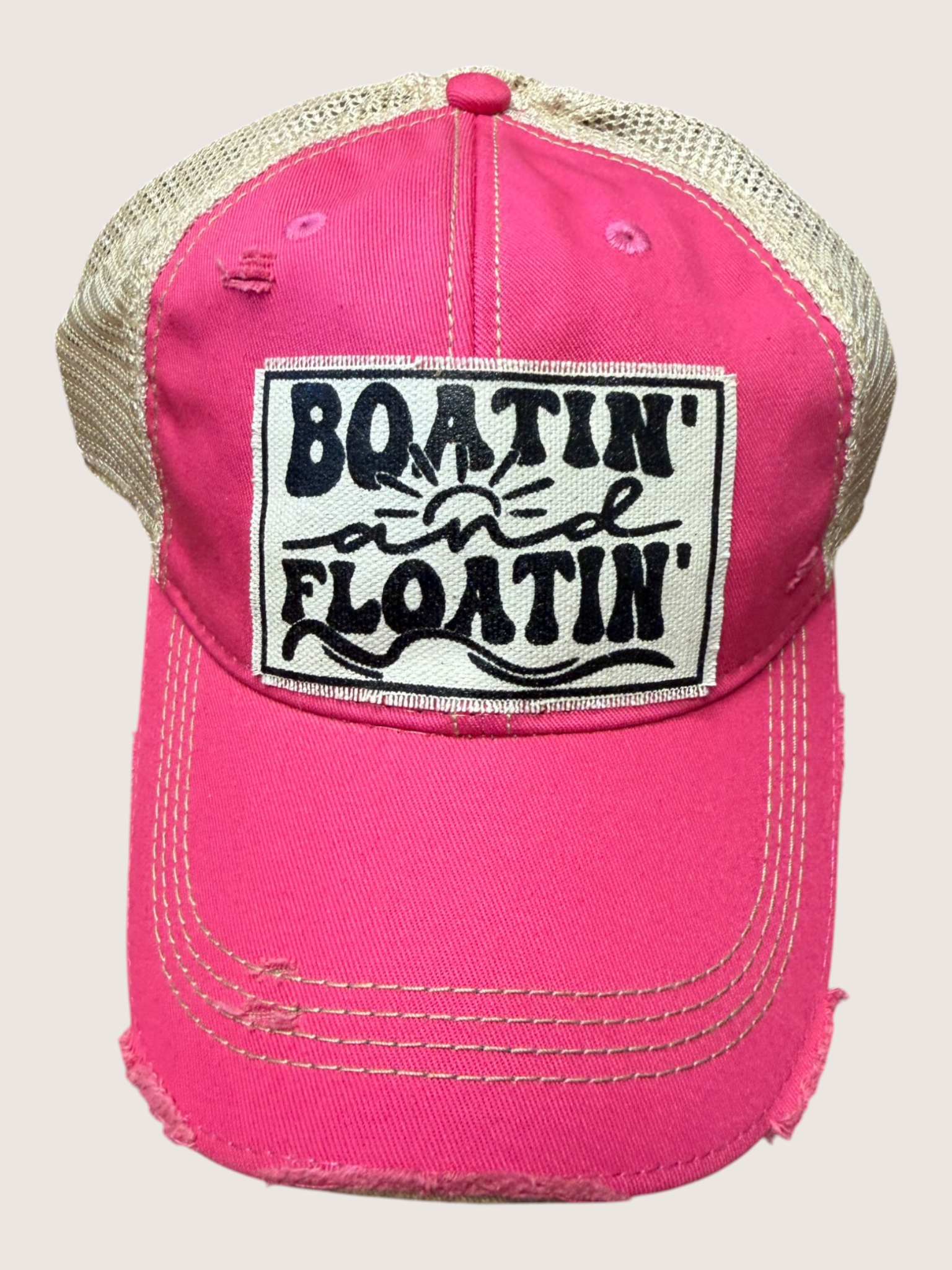 Pink cap with 'Boatin' and Floatin'' patch on a light gray background