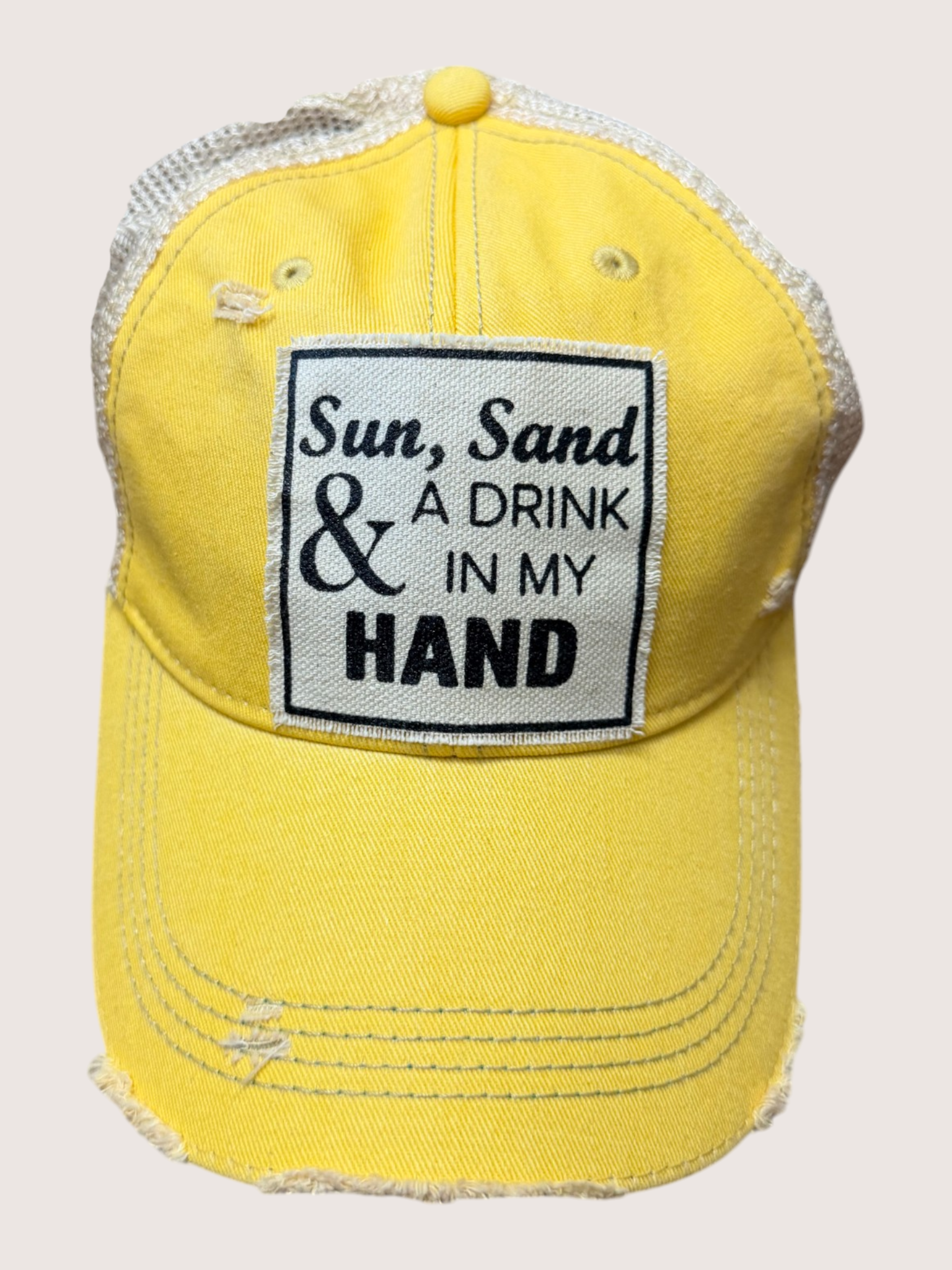 Yellow cap with a patch reading 'Sun, Sand & A Drink In My Hand' on a white background
