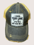 Denim cap with yellow brim and humorous patch on a light gray background