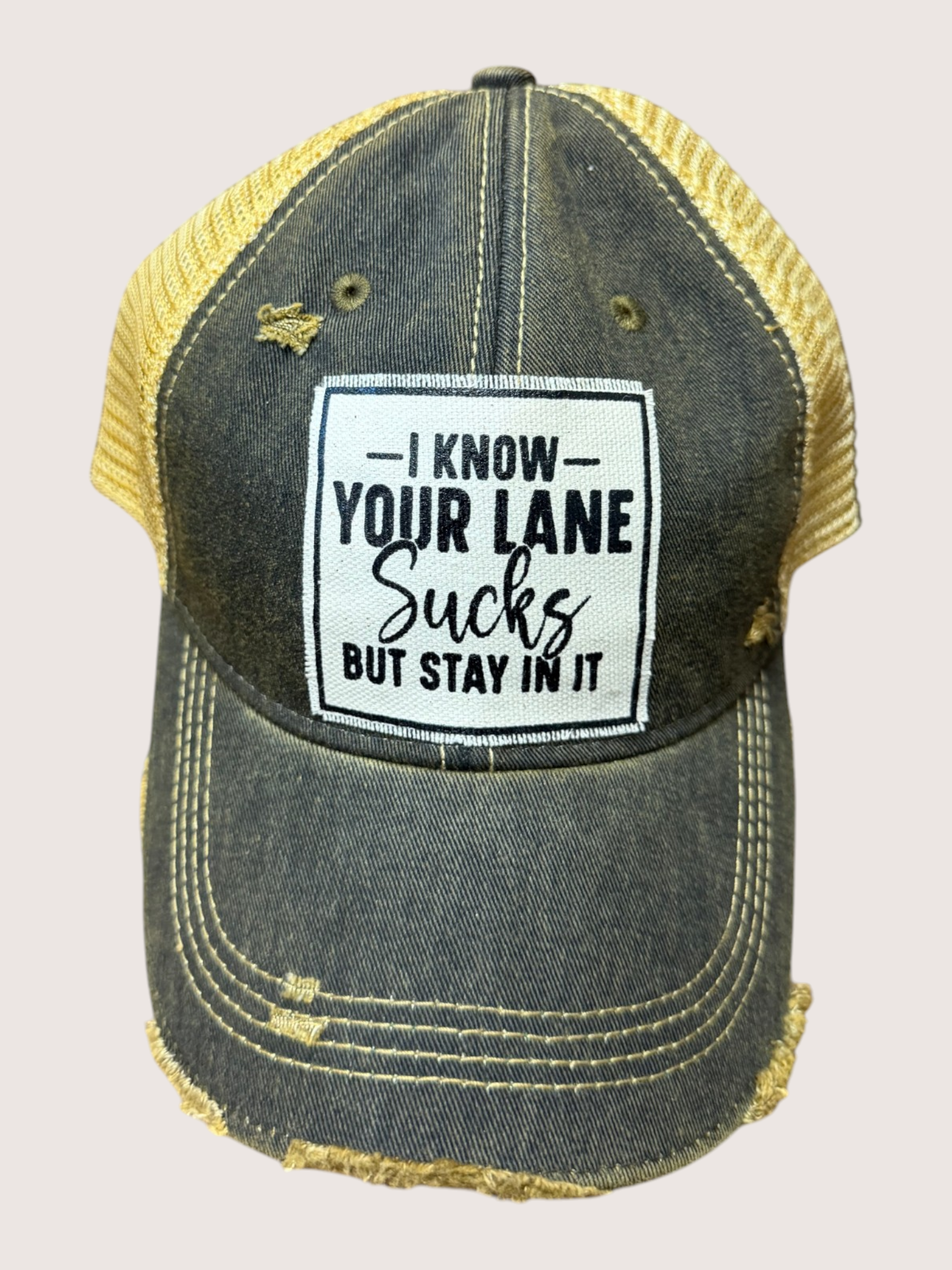 Denim cap with yellow brim and humorous patch on a light gray background