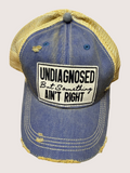Blue and yellow cap with a patch reading 'undiagnosed But Something Ain't Right' on a beige background
