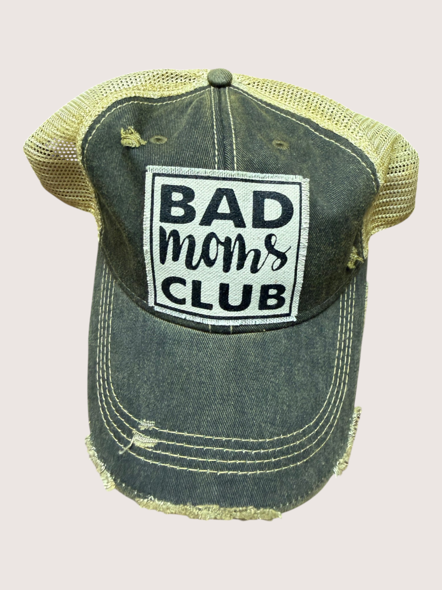 Vintage-style cap with 'Bad Moms Club' patch on a light pink background