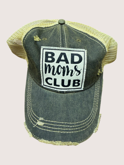 Vintage-style cap with 'Bad Moms Club' patch on a light pink background