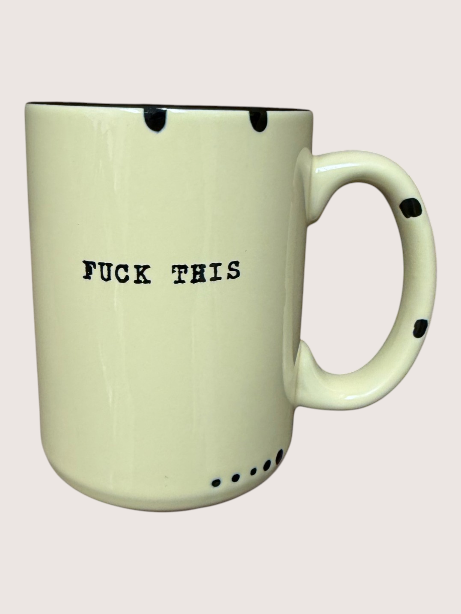 Light green mug with black text 'FUCK THIS' on a light pink background