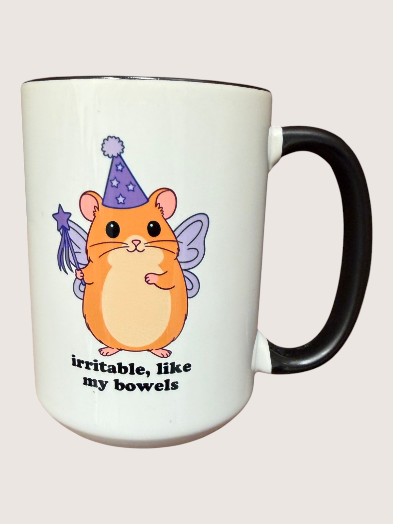 White mug with a cartoon hamster fairy design and text on a light pink background