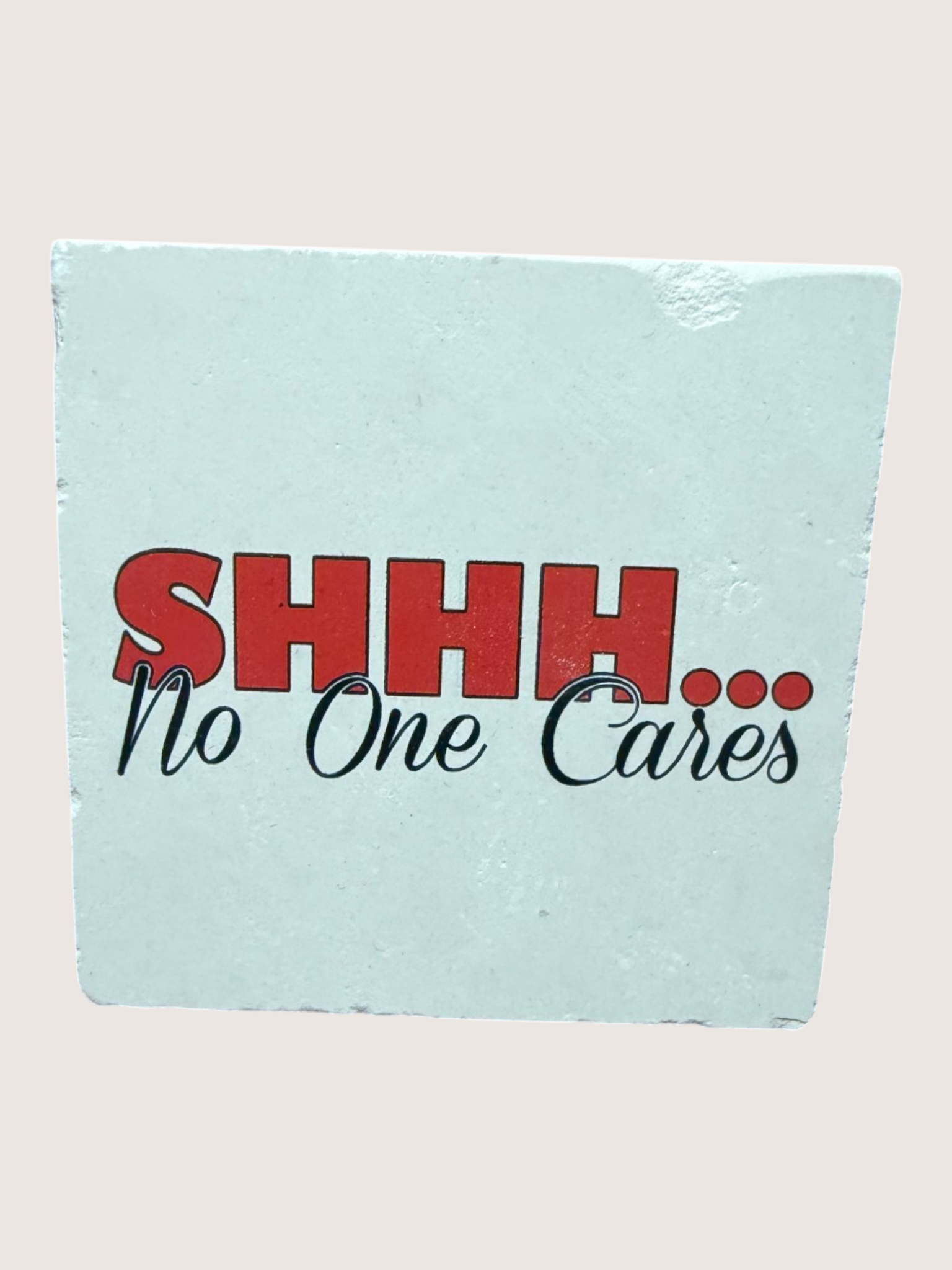 Light blue coaster with red and black text 'SHHH... No One Cares' on a beige background