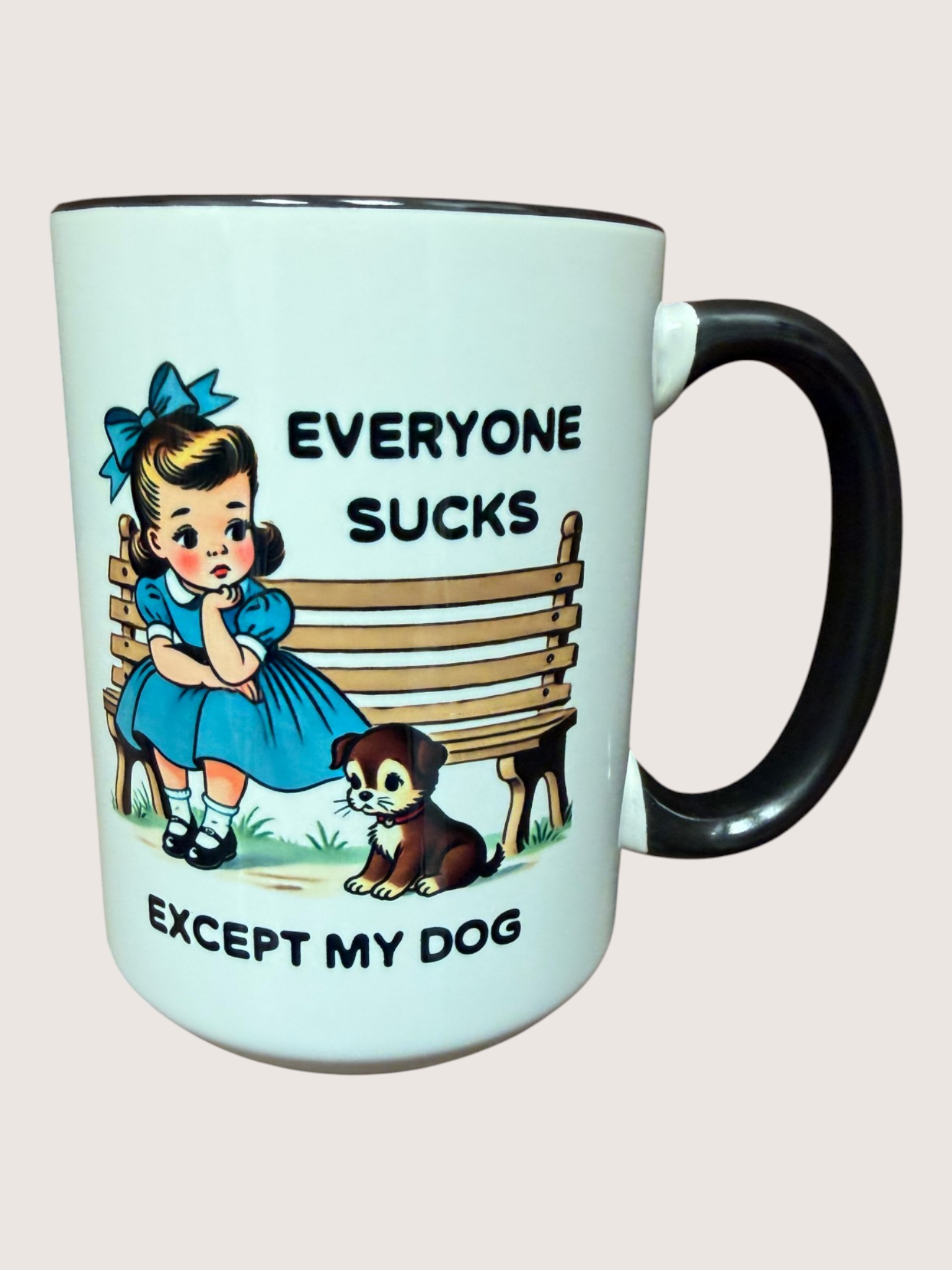 Mug with a cartoon design of a girl and dog on a bench with text 'Everyone sucks except my dog' on a light blue background.