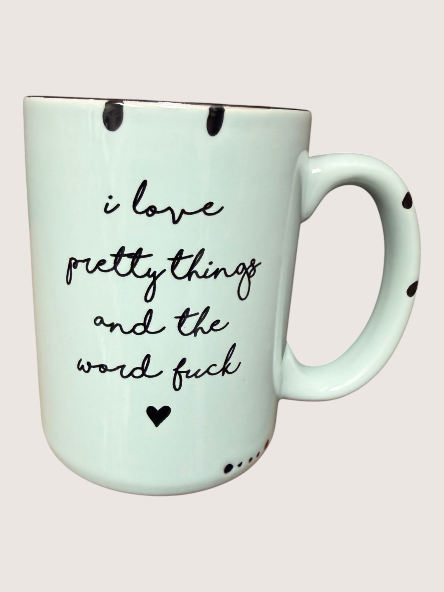 Mint green mug with black text and heart designs on a light pink background