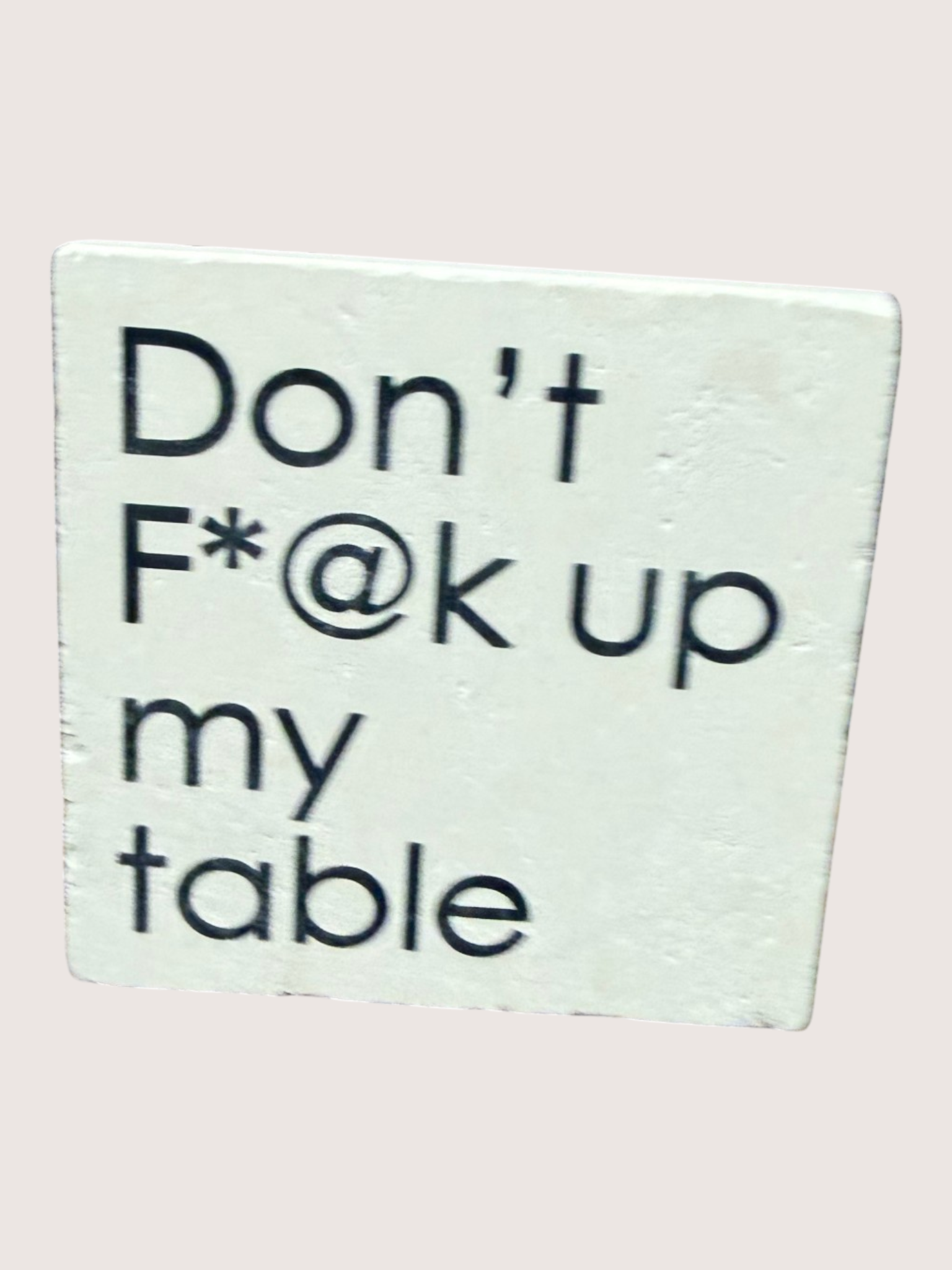 Text coaster with the message 'Don't F*@k up my table' on a light background