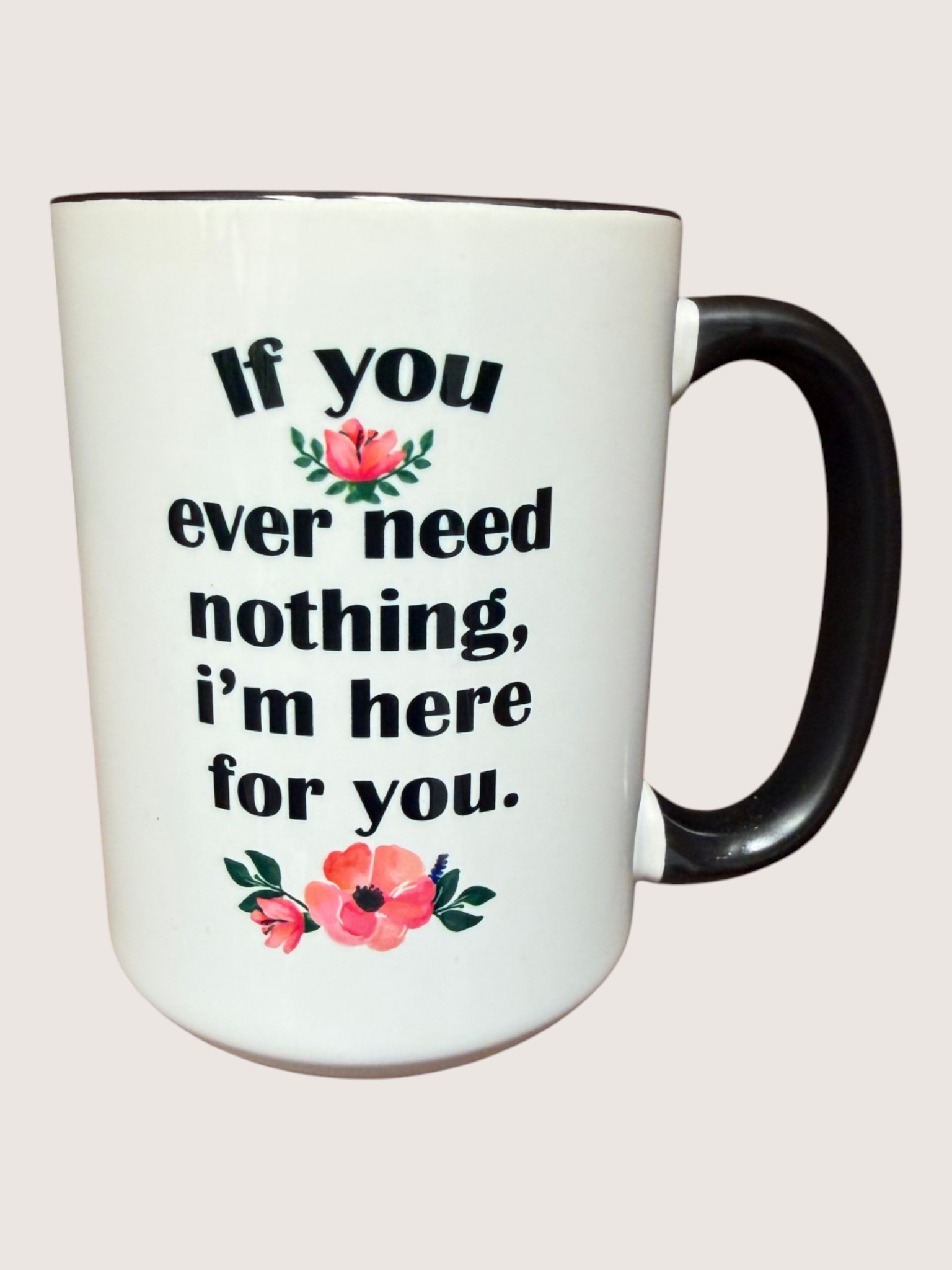 White mug with black handle featuring motivational quote and floral designs on a light pink background