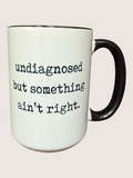 White mug with black text 'undiagnosed but something ain't right' on a white background