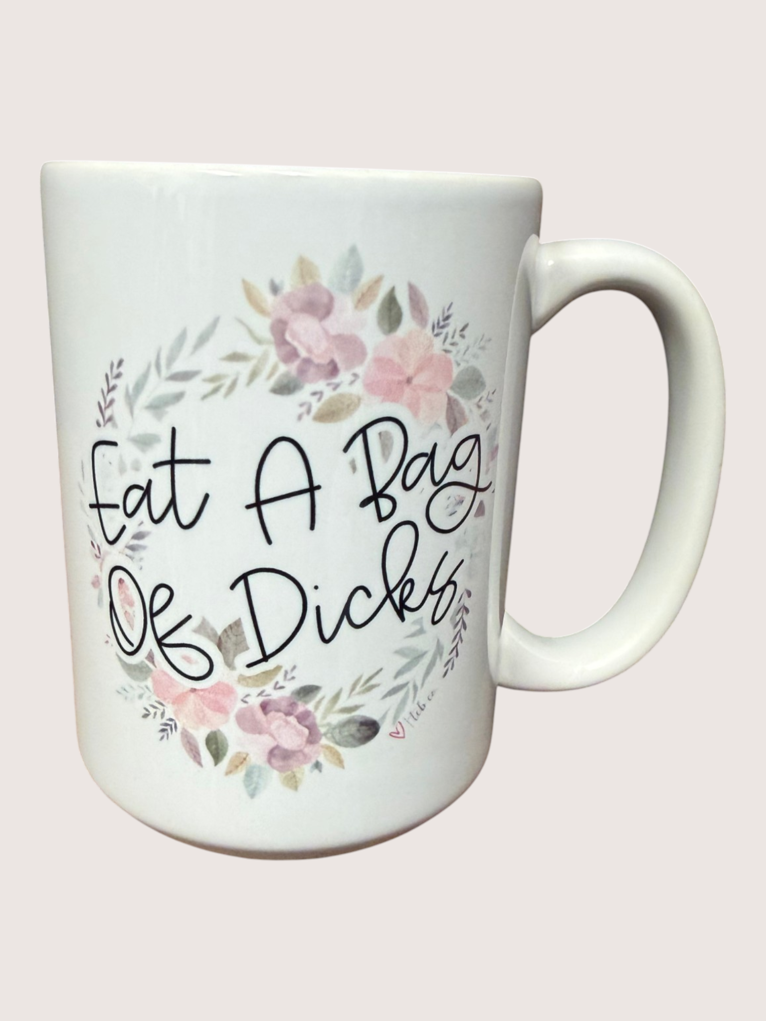 White mug with floral design and text on a light pink background
