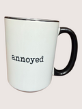 White mug with black handle and 'annoyed' text on a white background