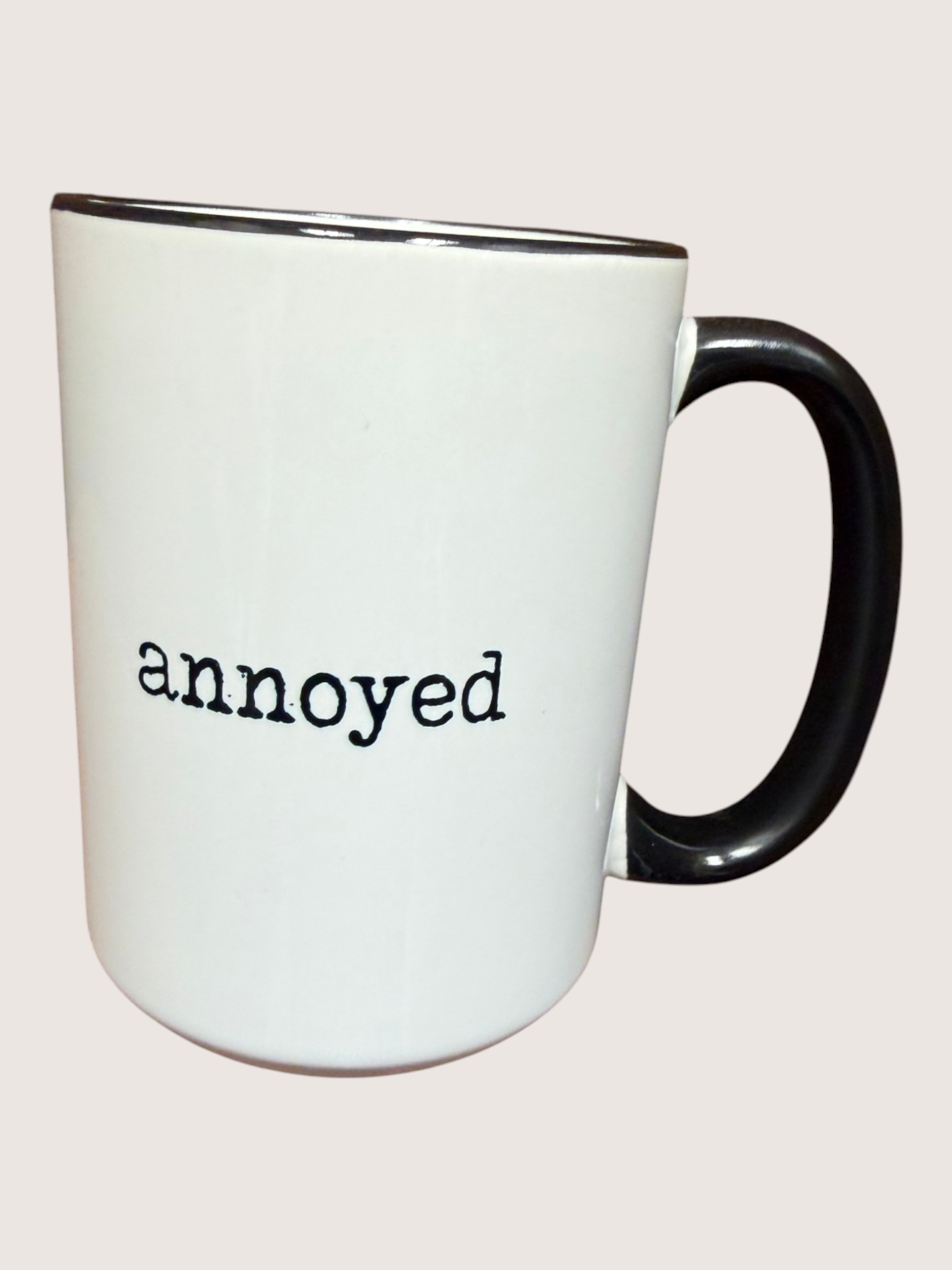 White mug with black handle and 'annoyed' text on a white background