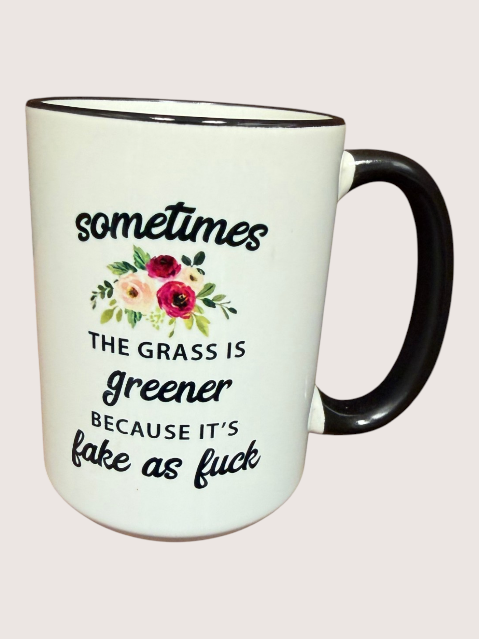 White mug with black handle featuring a floral design and text on a white background