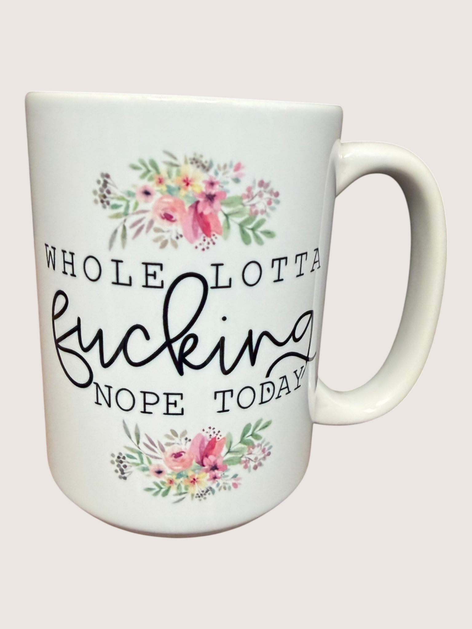 White mug with floral designs and text on a light pink background