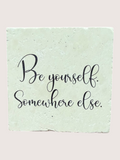 Motivational coaster 'Be yourself. Somewhere else.' on a textured green background