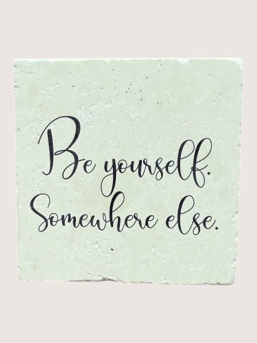 Motivational coaster 'Be yourself. Somewhere else.' on a textured green background