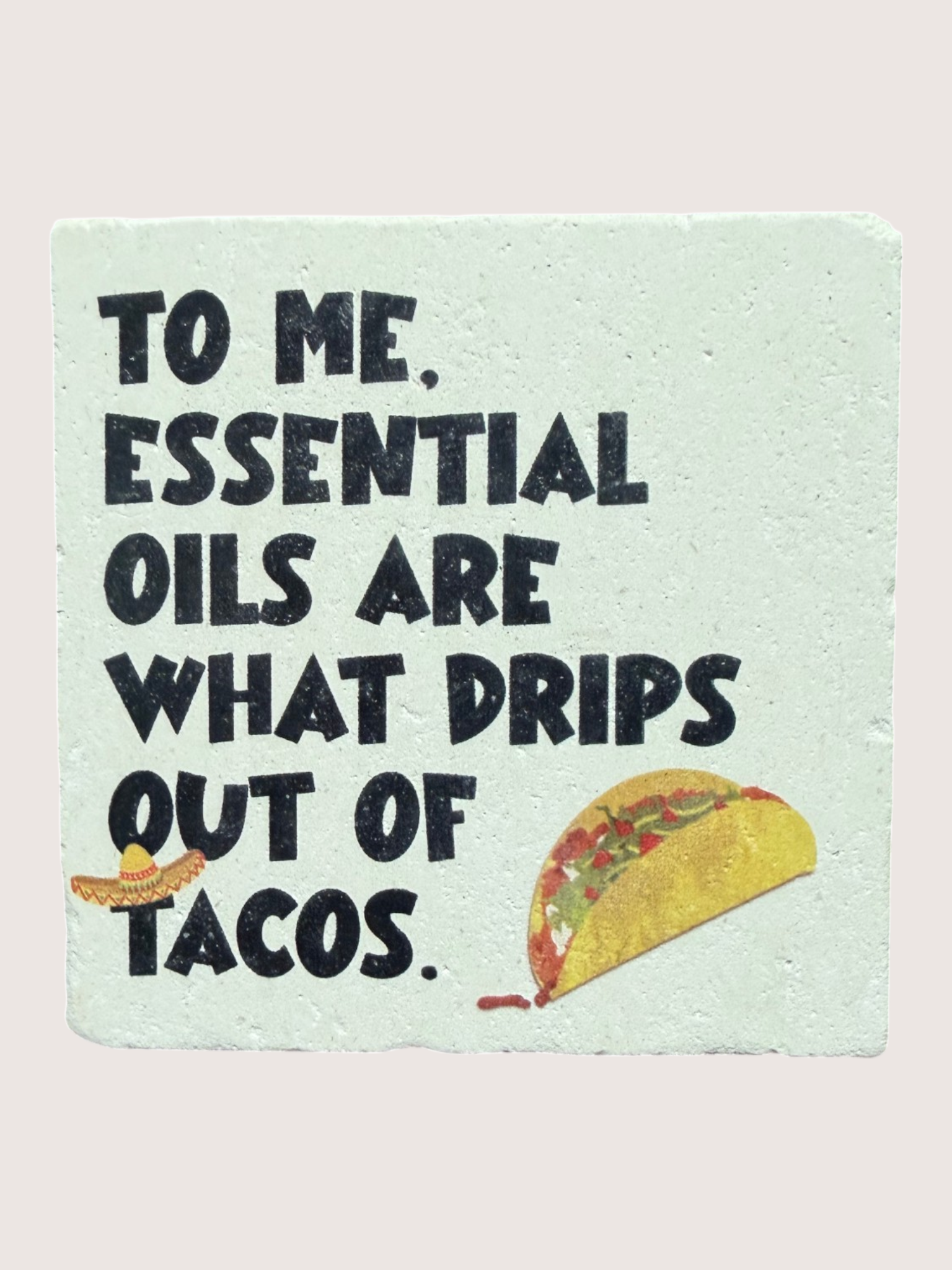 coaster with text 'To me, essential oils are what drips out of tacos' on a light blue background.