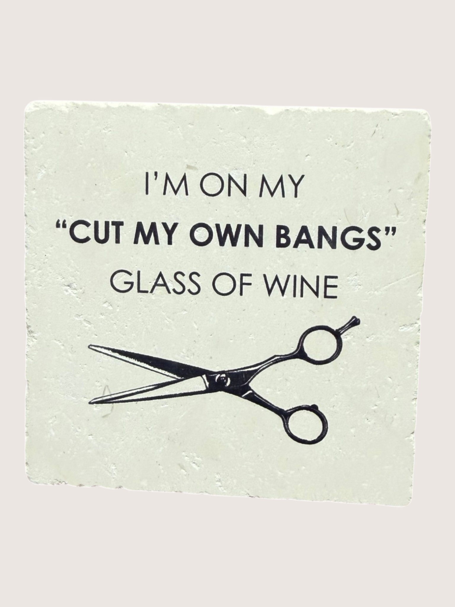 Coaster with text 'I'm on my 'Cut my own bangs' glass of wine' and a pair of scissors on a light green background.