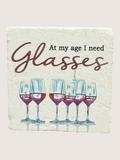 Coaster with wine glasses and text 'At my age I need glasses' on a light background